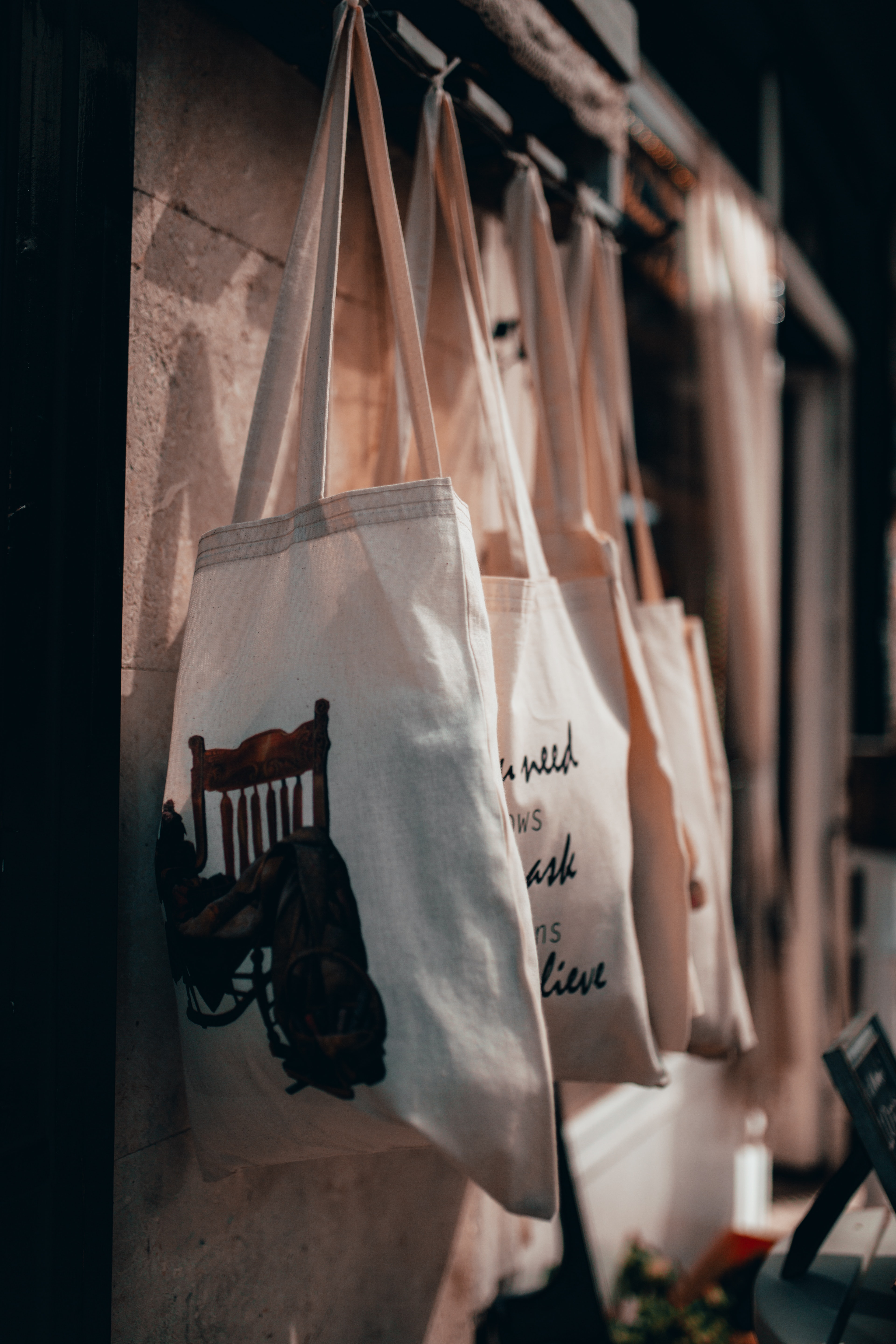 cloth-tote-bags-with-assorted-prints-hanging-on-a-rack-3185223